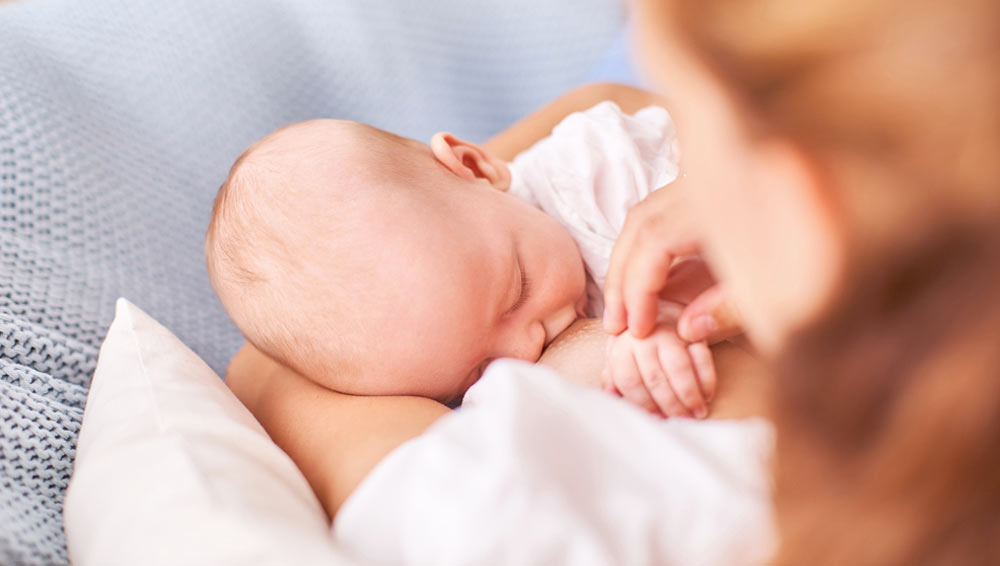 A mother breastfeeding her newborn, representing the ideal nutrition that targeted fortification aims to optimize for vulnerable preterm infants.
