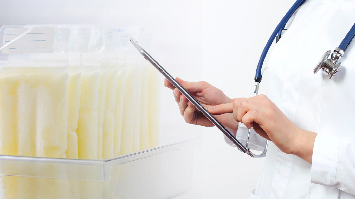 A healthcare professional in a human milk bank reviewing stored milk donations, a process that can be optimized with digital tracking and management software.