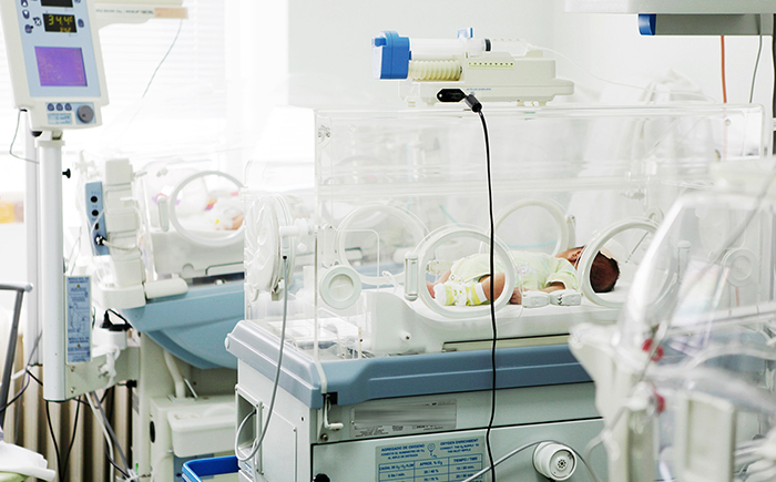 Rows of incubators in a Neonatal Intensive Care Unit, representing the clinical setting where targeted fortification improves outcomes and reduces costs.