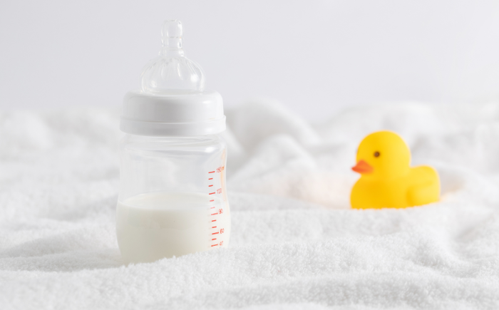 A rubber duck in a bowl of milk, symbolizing the delicate balance and potential risks of infant feeding, specifically related to milk osmolality.
