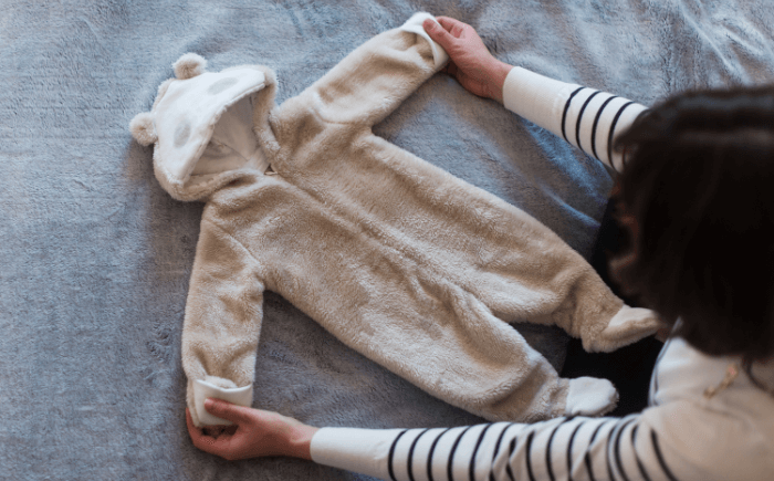 A premature baby outfit to keep dressed in a warm, layered onesie with a hat and socks to prevent heat loss during winter.